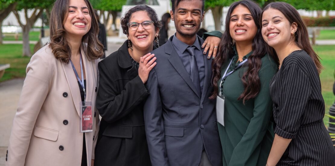A group of diverse colleagues smiling together, showcasing teamwork and friendship outdoors.